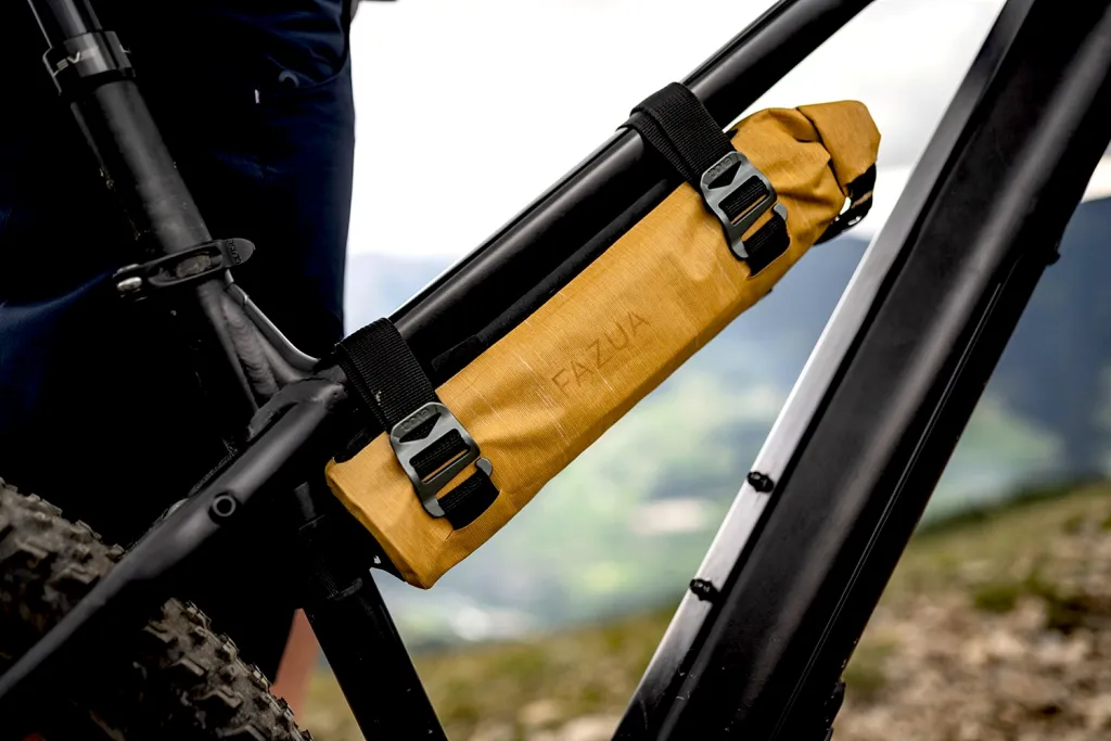 Fazua 250x accu in een beschermende accu tas, gemonteerd op het frame van een elektrische fiets. Op de achtergrond zie je bergen.